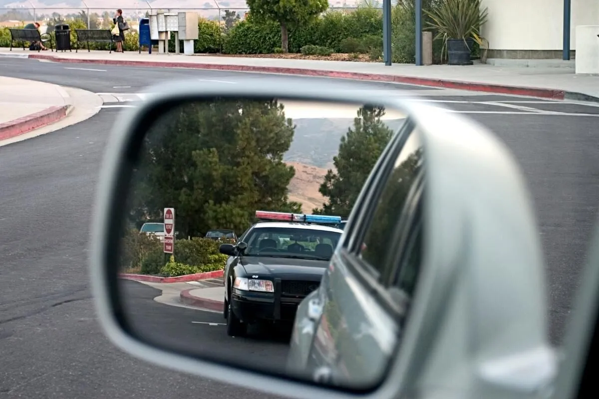 Reflection of a police car in a side-view mirror, representing car accident and traffic offense legal services in Royal Oak MI.